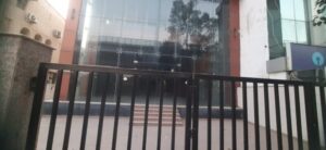 Modern commercial building facade with secure gated entry, lift access, and dedicated parking in Okhla Phase 2.