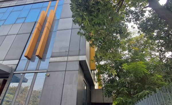 Modern commercial industrial building exterior with wide access driveway and parking in Okhla Phase 2.