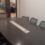Professional boardroom table with seating and presentation screen setup in a furnished office rental in Okhla.