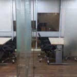 Private glass-partitioned executive cabin with manager desk inside a furnished office on rent in Okhla Phase 2.