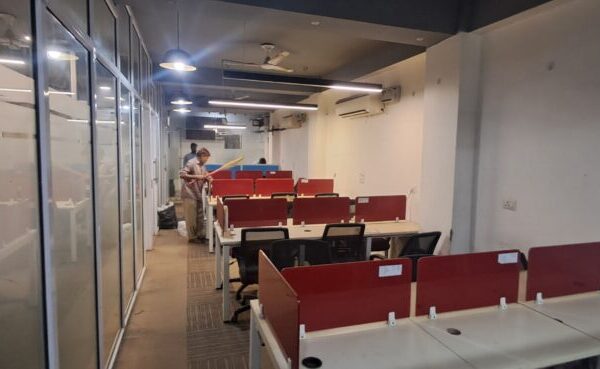 Modern office workstations and glass-partitioned cabin inside an Okhla Phase 2 DDA shed unit.