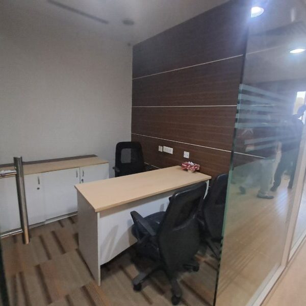 Glass-partitioned private manager cabin with executive desk inside a furnished office lease unit in Okhla.